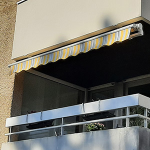 Pose d'un store pour protéger le balcon d'un appartement du soleil.
